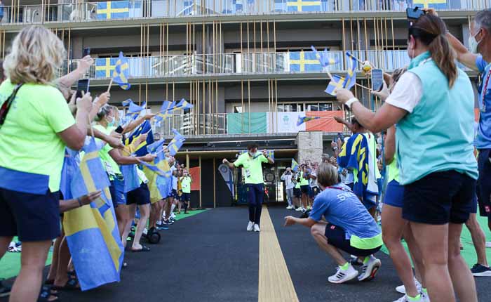 Massor av gul- och blåklädda människor viftar med svenska flaggor och klappar i händerna kring en dansade guldmedaljör. 