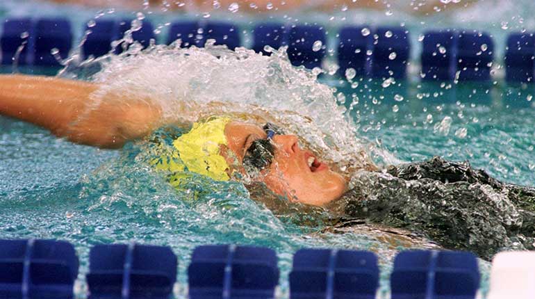 En närbild på en simmare med gul badmössa som simmar ryggsim. Foto: SOK