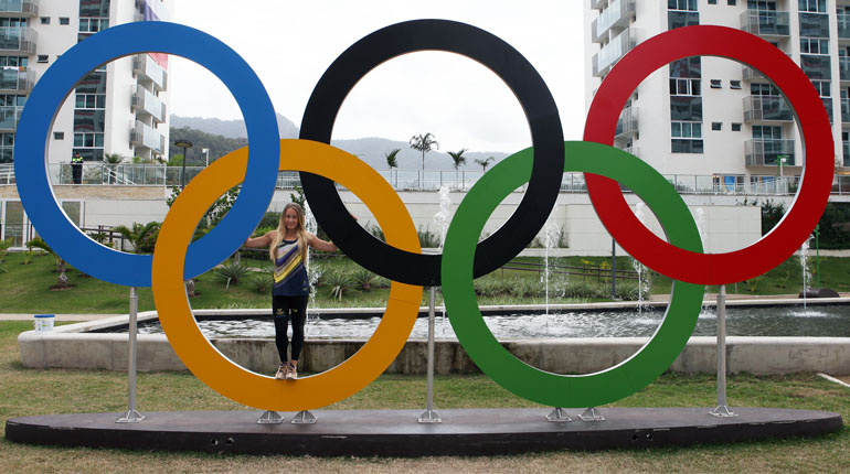 Emma Larsson bland OS-ringarna som står mitt i OS-byn. Foto: SOK