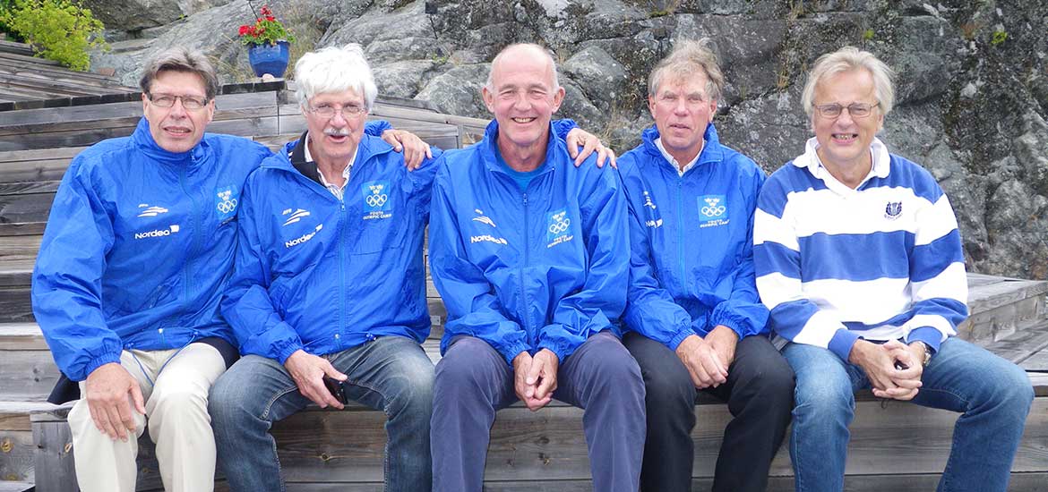 Fem leende äldre män sitter på rad med blåa jackor med Sveriges Olympiska Kommittés emblem. 