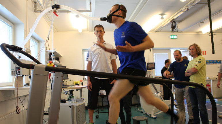 Ludvig Billtoft på löpbandet pressar sitt yttersta medan han övervakas av träningsrådgivaren Rickard Nilsson (näst längst till höger) och sportchefen Anders Wiggerud (längst till höger). Foto: SOK