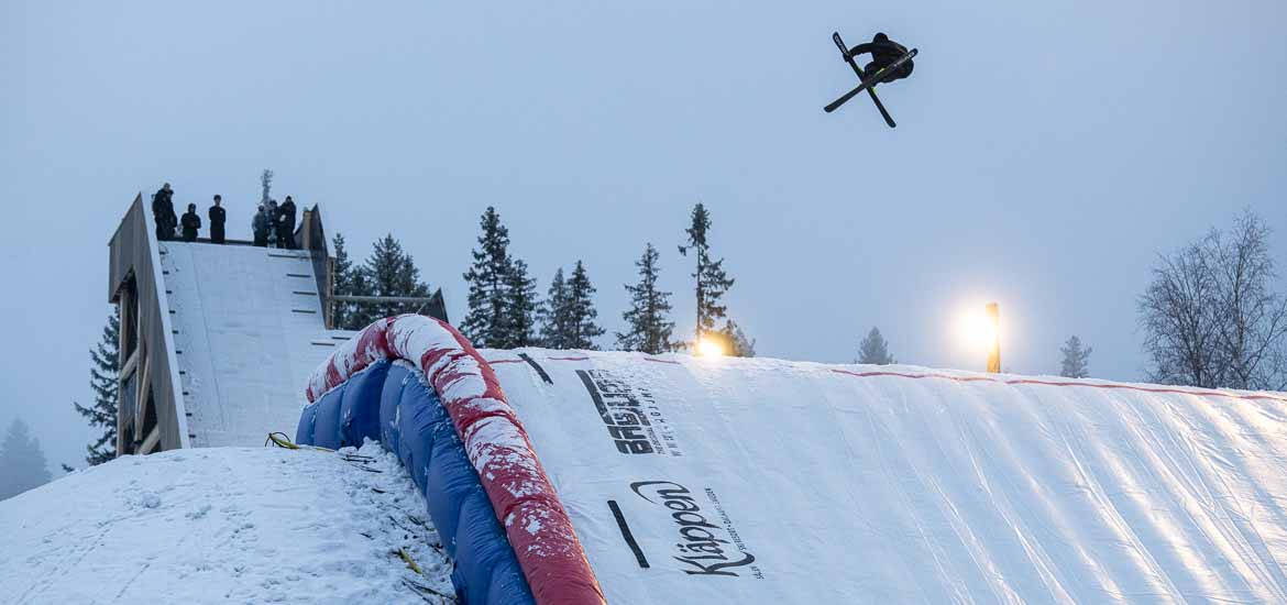 En skidåkare utför ett trick högt uppe i luften med en stor uppblåst landningskudde undertill. 